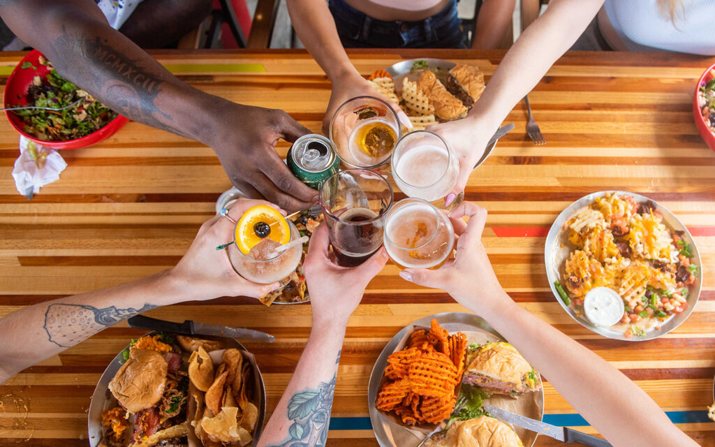 Friends clinking drinks over table